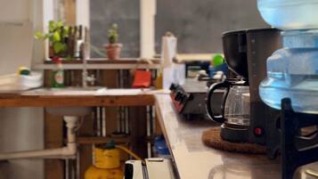 A kitchen with a water dispenser, coffee maker, and a yellow gas cylinder.