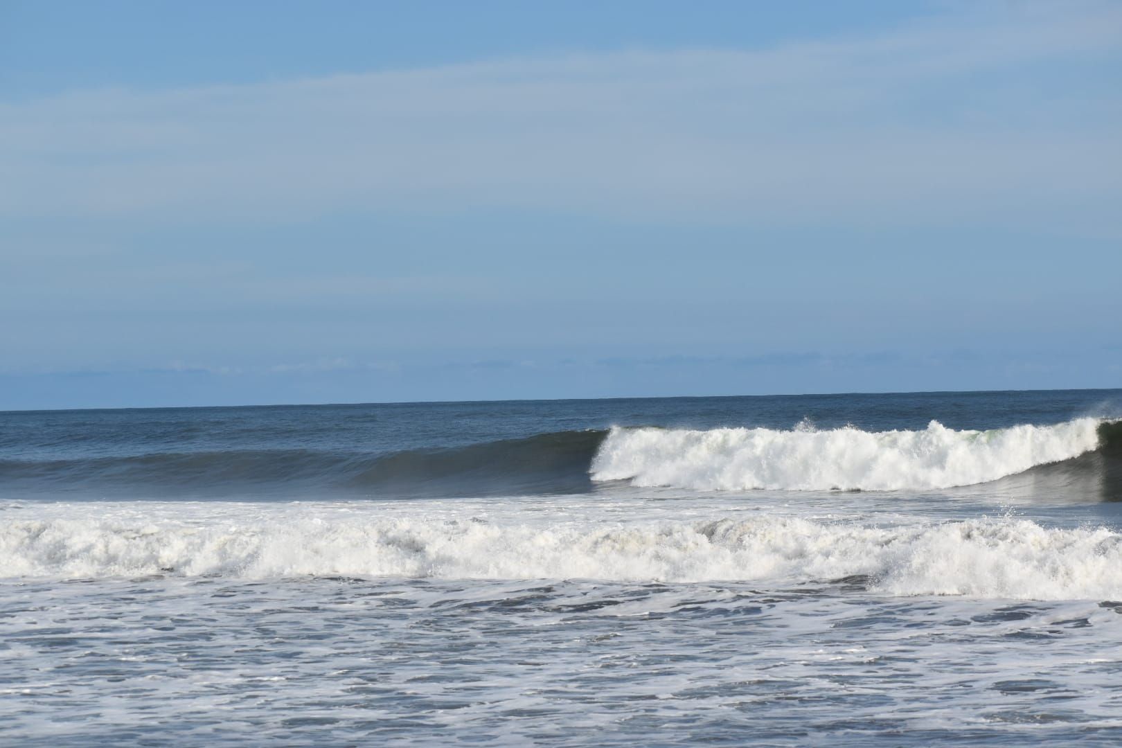 A beach with waves and a clear sky.