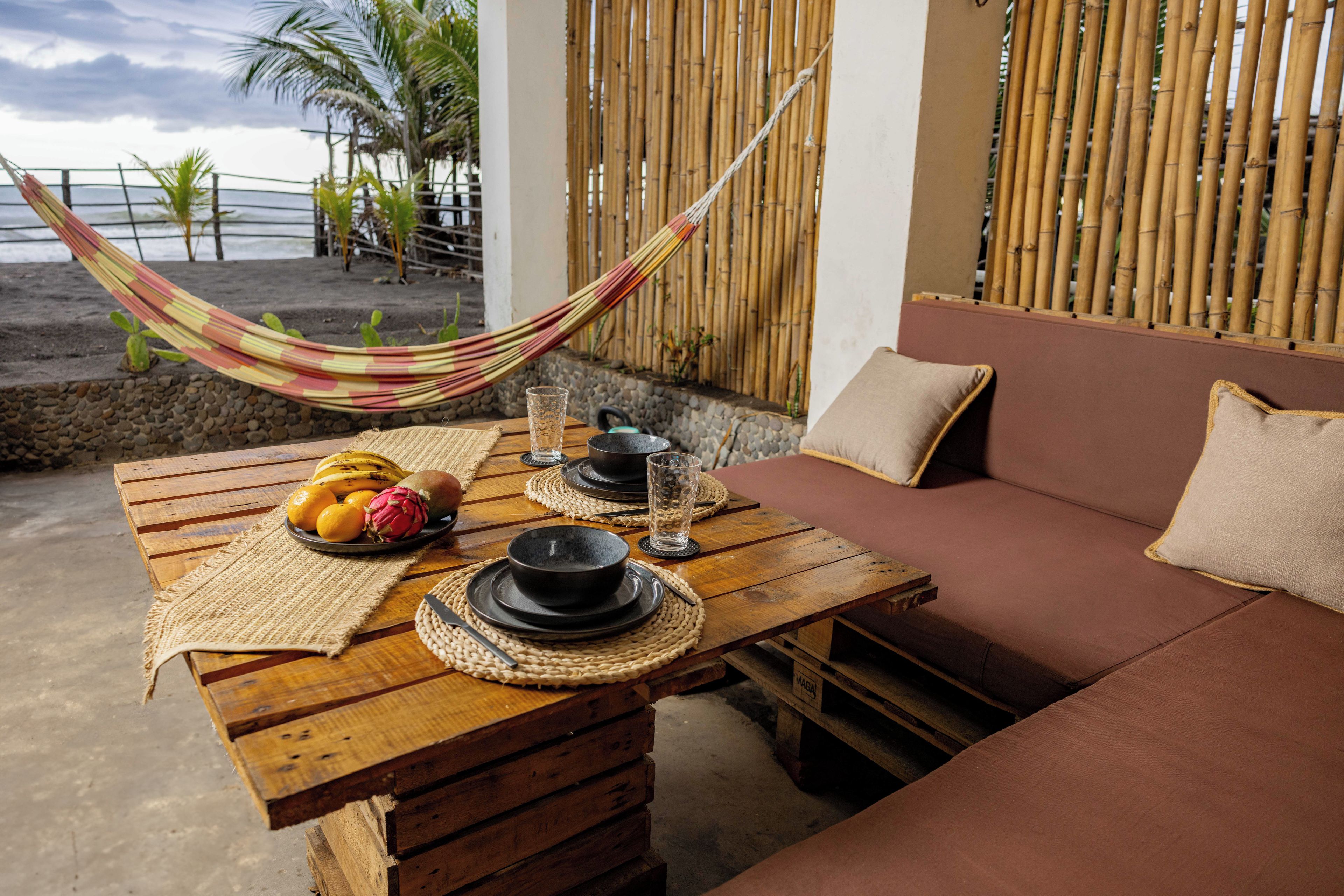 A wooden table with a woven placemat, a bowl of fruit, and a glass of water.
