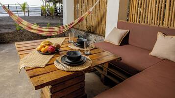 A wooden table with a woven placemat, a bowl of fruit, and a glass of water.
