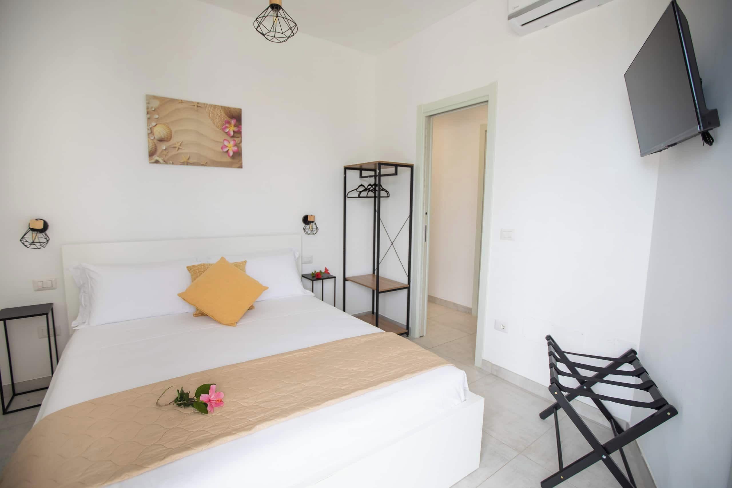 Une chambre d’hôtel avec un grand lit, un téléviseur fixé au mur et une armoire avec un miroir.