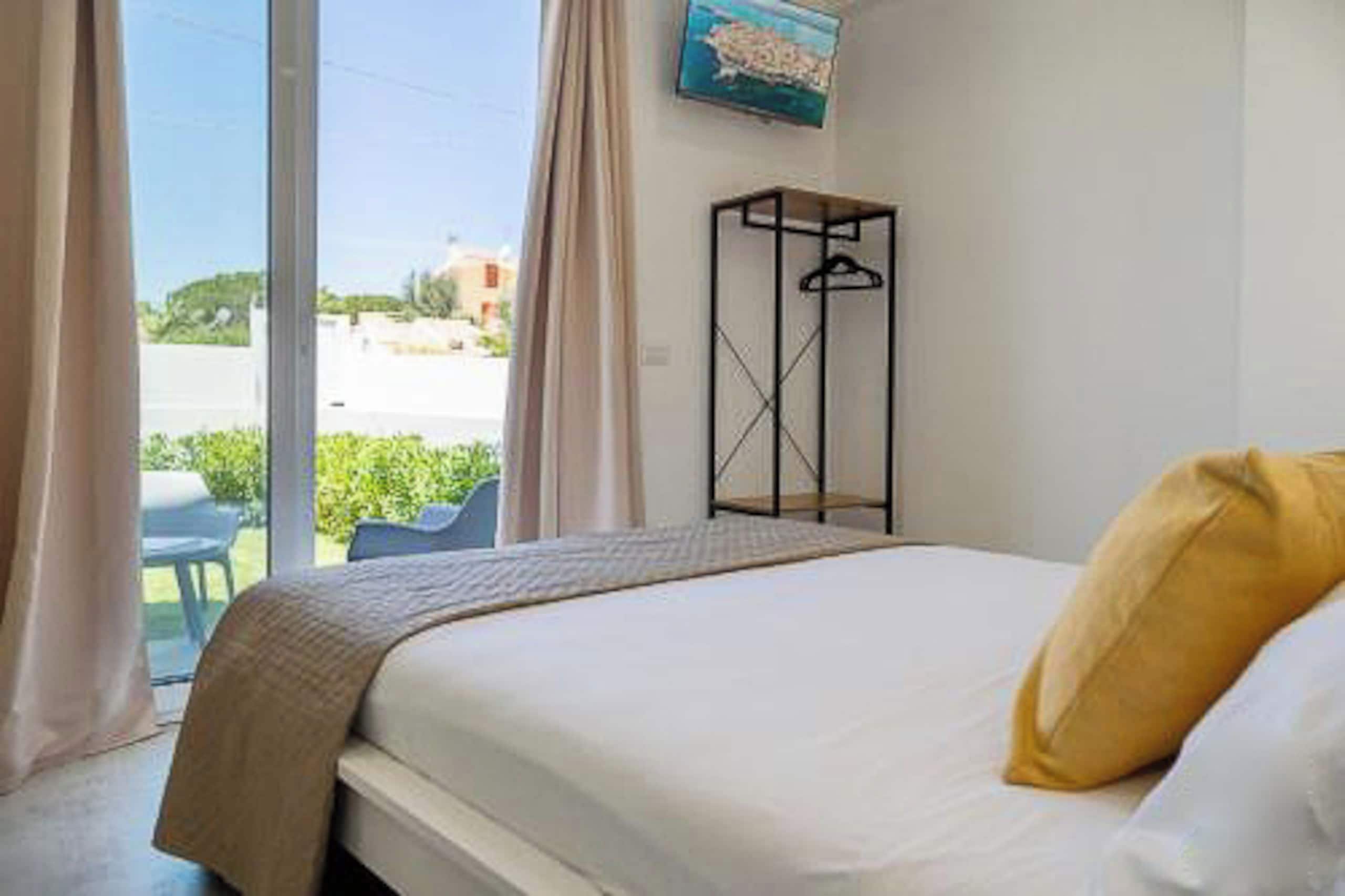 Ein Hotelzimmer mit Bett, Kleiderhaken und Blick ins Freie.