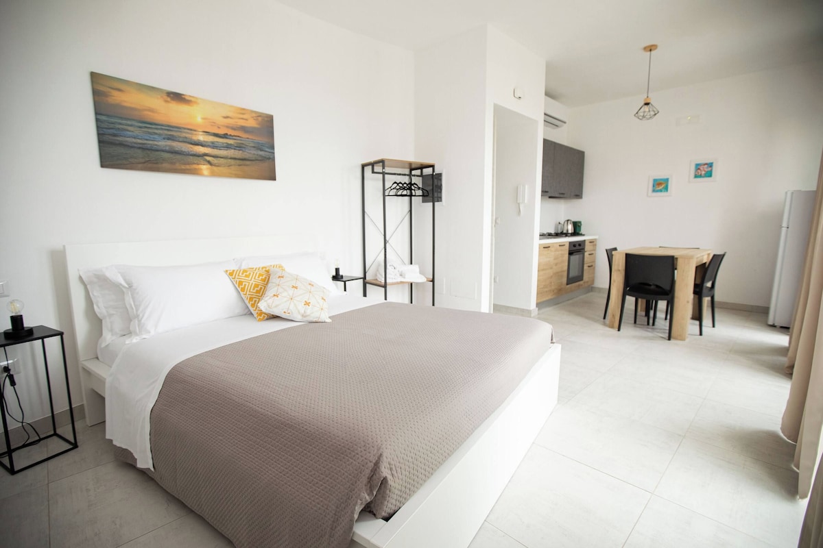 A bedroom with a bed, bedside table, and a painting on the wall.