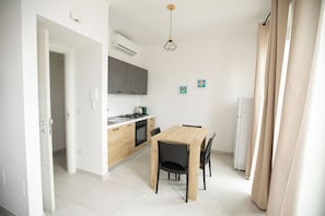 Una cocina moderna con una mesa de comedor y sillas, un refrigerador y una estufa.