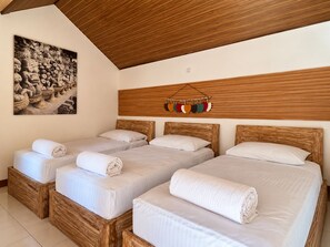 A hotel room with three wooden beds, a wooden ceiling, and a wall-mounted artwork. - OYO 95446 Golden Homestay (Medan)