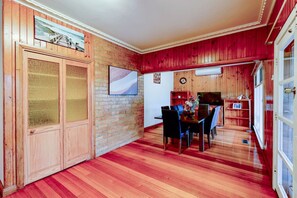 Un comedor con pared de ladrillo, armarios de madera y suelo rojo.