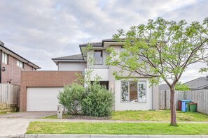 A two-story residential building with a garage, a small front yard with a tree, and a neighboring house. - StayAU Luxury Double-Story Home | A/C Throughout (Clyde)