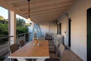 A covered outdoor dining area with a wooden table, wicker chairs, and a blue ladder. - House in Kassiopi village, 400m from sea (Kassiopi)