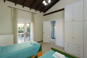 Ein Zimmer mit zwei Betten, einem Kleiderschrank und einer Tür zu einem Außenbereich.