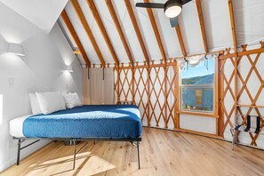 A bedroom with a bed, wooden beams, a window, and a view. - Oso Blue - The Black Bear (Garden City)