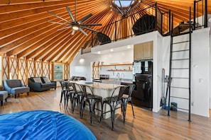 Ein geräumiges Loft mit hoher Decke, einem zentralen Essbereich und einer Küche mit modernen Geräten.