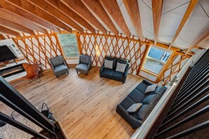 An interior with a wooden ceiling, a sofa set, a fireplace, and a window. - Oso Blue - The Cisco | Yurt Experience! Outdoor Games, BBQ, Views, & More (Garden City)