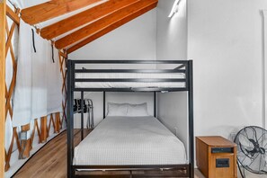 A bunk bed with a wooden frame and white bedding, a fan, and a small wooden cabinet. - Oso Blue - The Rendezvous | Yurt Experience! Outdoor Games, BBQ, Views, & More (Garden City)