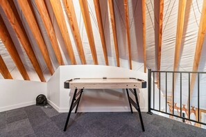 Una habitación con techo inclinado, un banco de trabajo y un ventilador negro.