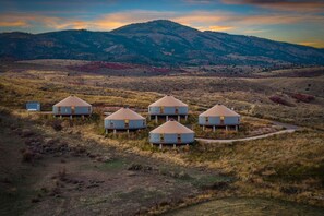 A group of yurts in a natural setting with a mountainous backdrop. - Oso Blue | 5 Yurt Compound! Sleeps 60! Lawn Games! BBQs! (Garden City)