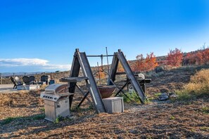 A rural landscape with a metal structure, possibly a water pump, and a grill.