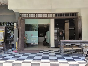 Una cafeteria amb un terra de pissos, una barra amb caires i una porta de vidre que dona a l'interior.