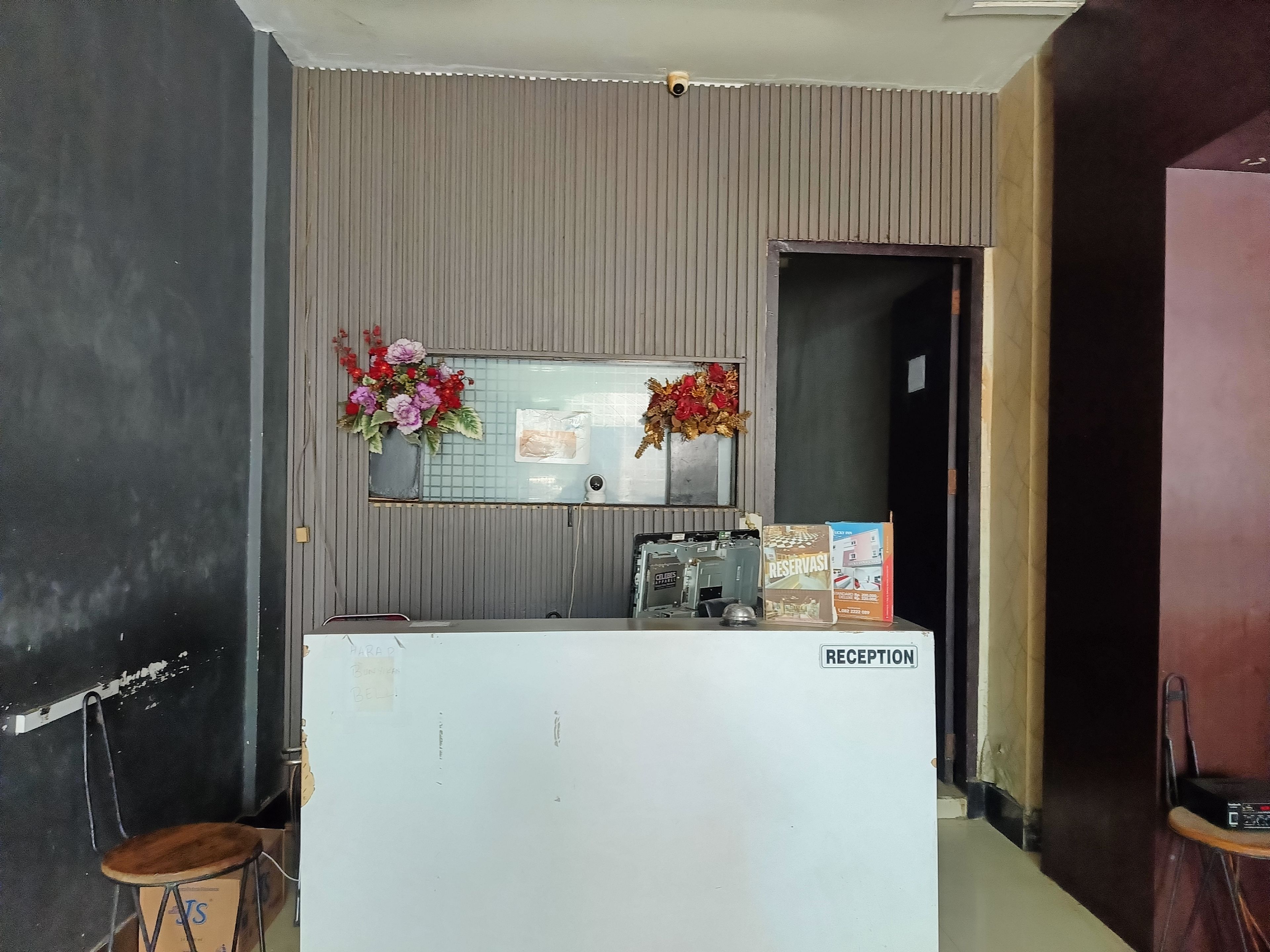 A reception desk with a mirror, a potted plant, and a sign labeled 'RECEPTION'.