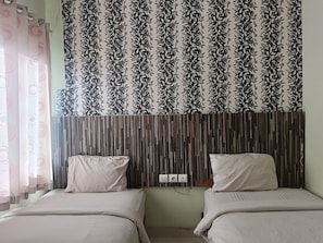 A room with two beds, a patterned curtain, and a wooden headboard. - Hotel O near Mall Panakkukang (Makassar)