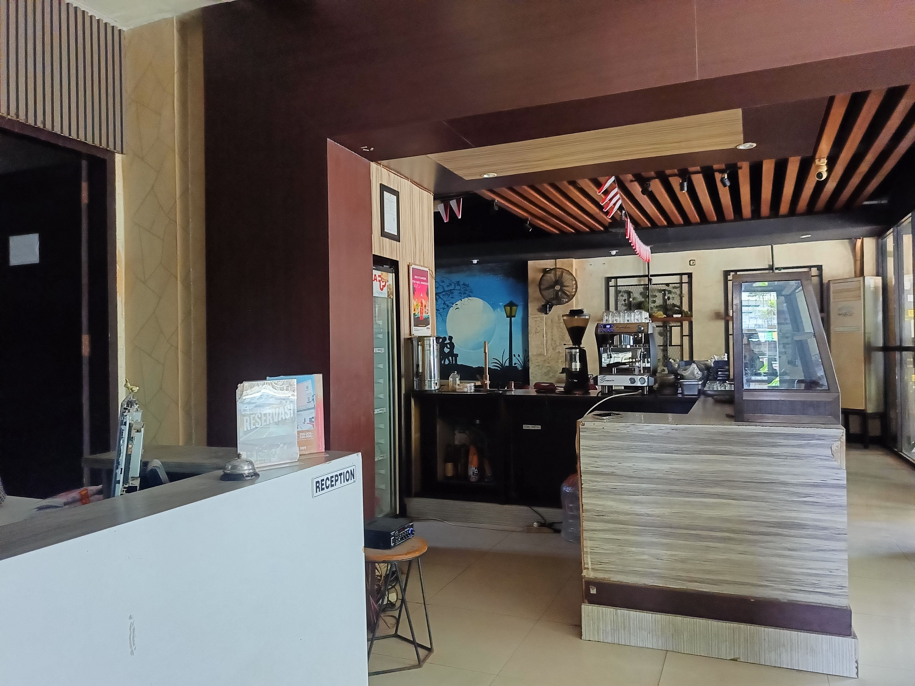 A reception area with a counter, a coffee machine, and a wall with a poster.