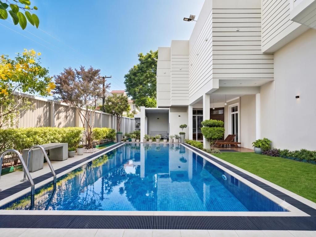 Un edificio residencial moderno con piscina, un patio cubierto y un jardín bien cuidado.