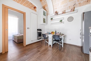 A modern kitchen with a dining area, wooden flooring, and a built-in refrigerator.