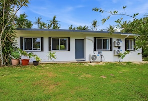 A single-story house with a flat roof, a front door, and two windows on the ground floor. There are two air conditioning units mounted on the exterior wall. -  Private beach with pathway to spacious 3 bedroom home (Hågat)