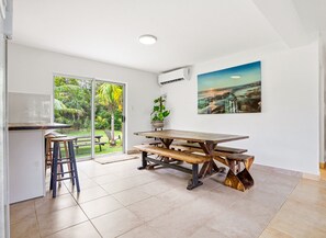 Eine Küche mit Holztisch und Hockern, einer Schiebetür zum Garten und einem Bild an der Wand.