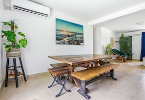 A dining area with a wooden table and benches, a potted plant, and a painting on the wall. -  Private beach with pathway to spacious 3 bedroom home (Hågat)