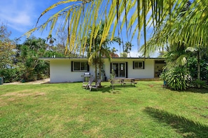 A single-story house with a grassy yard, a patio with a table and chairs, and a small garden area with various plants. -  Private beach with pathway to spacious 3 bedroom home (Hågat)