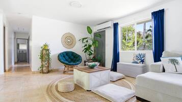 Una sala de estar moderna con un sofá, una silla, una mesa de centro y un ventanal con cortinas.