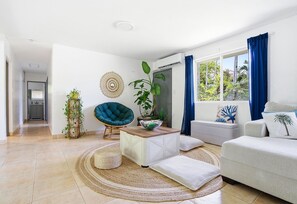 A modern living room with a sofa, a chair, a coffee table, and a large window with curtains.