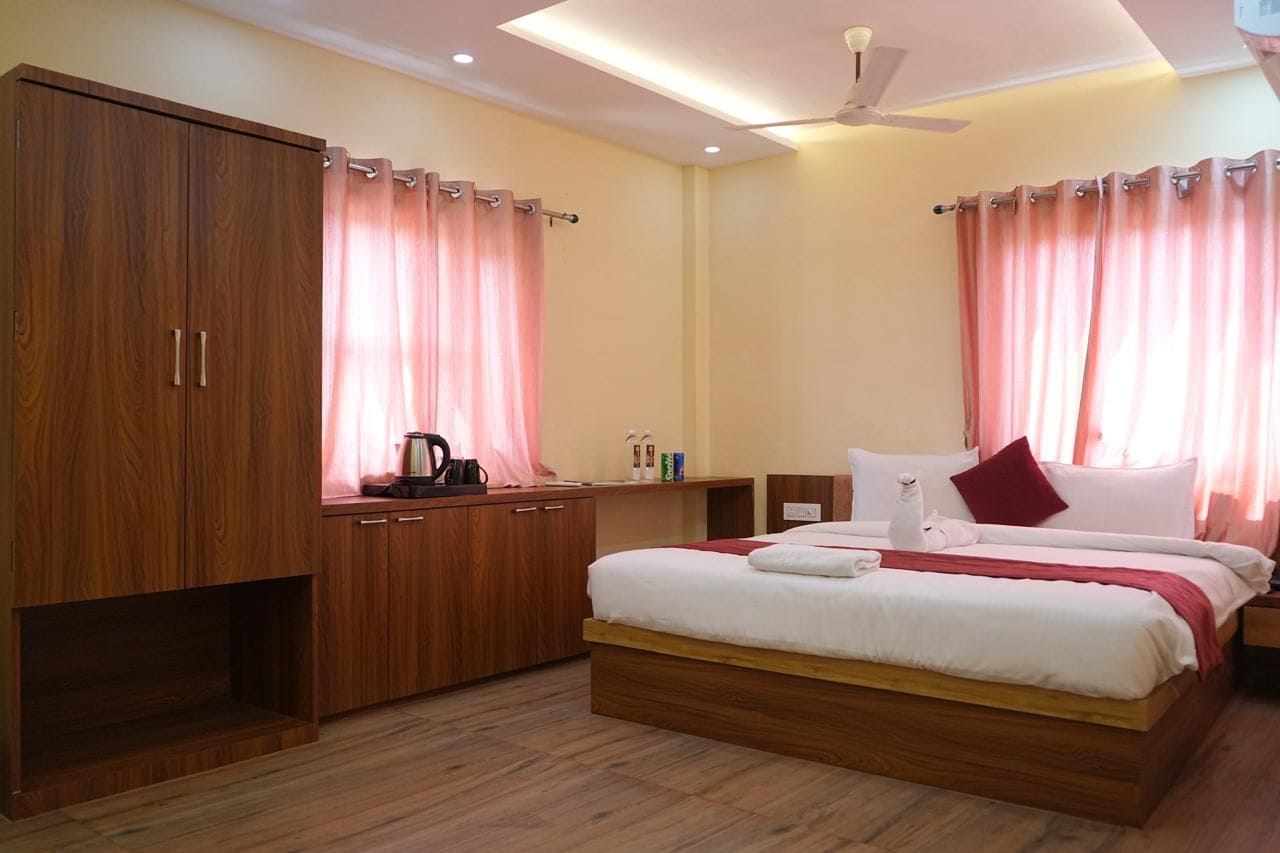 Una habitación de hotel con un armario de madera, una cama con ropa de cama blanca, un cojín rojo y un ventilador de techo.