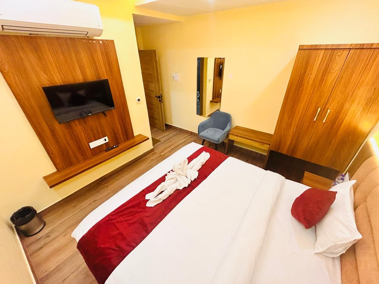Een hotelkamer met een bed, een aan een houten paneel bevestigde televisie, een stoel en een kledingkast.