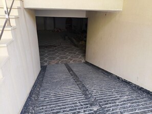 A narrow corridor with a patterned floor leading to a room with a tiled wall and a door. - Hotel Shiv Sadhana (Varanasi)