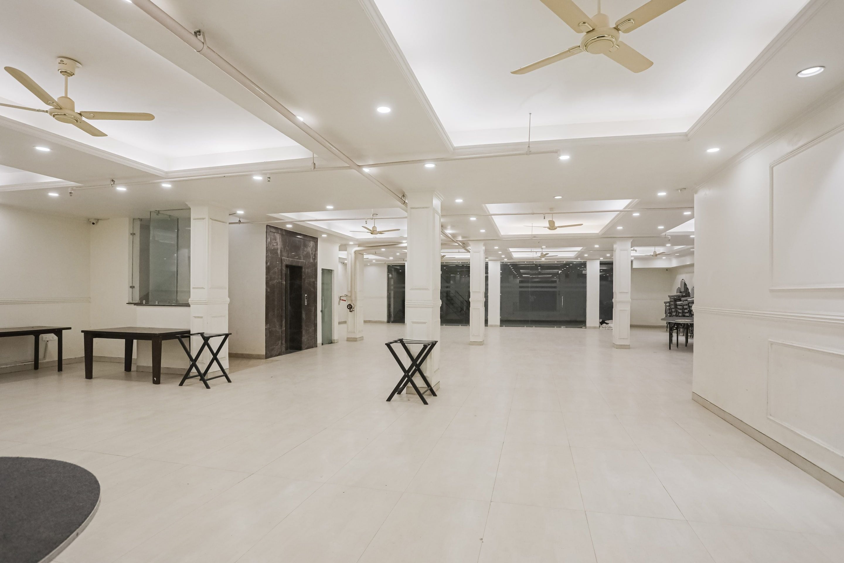 A spacious, well-lit room with ceiling fans, a large table, and a seating area.