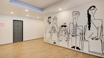 A spacious room with a wooden floor, a grey door, and a wall mural depicting cartoon characters.