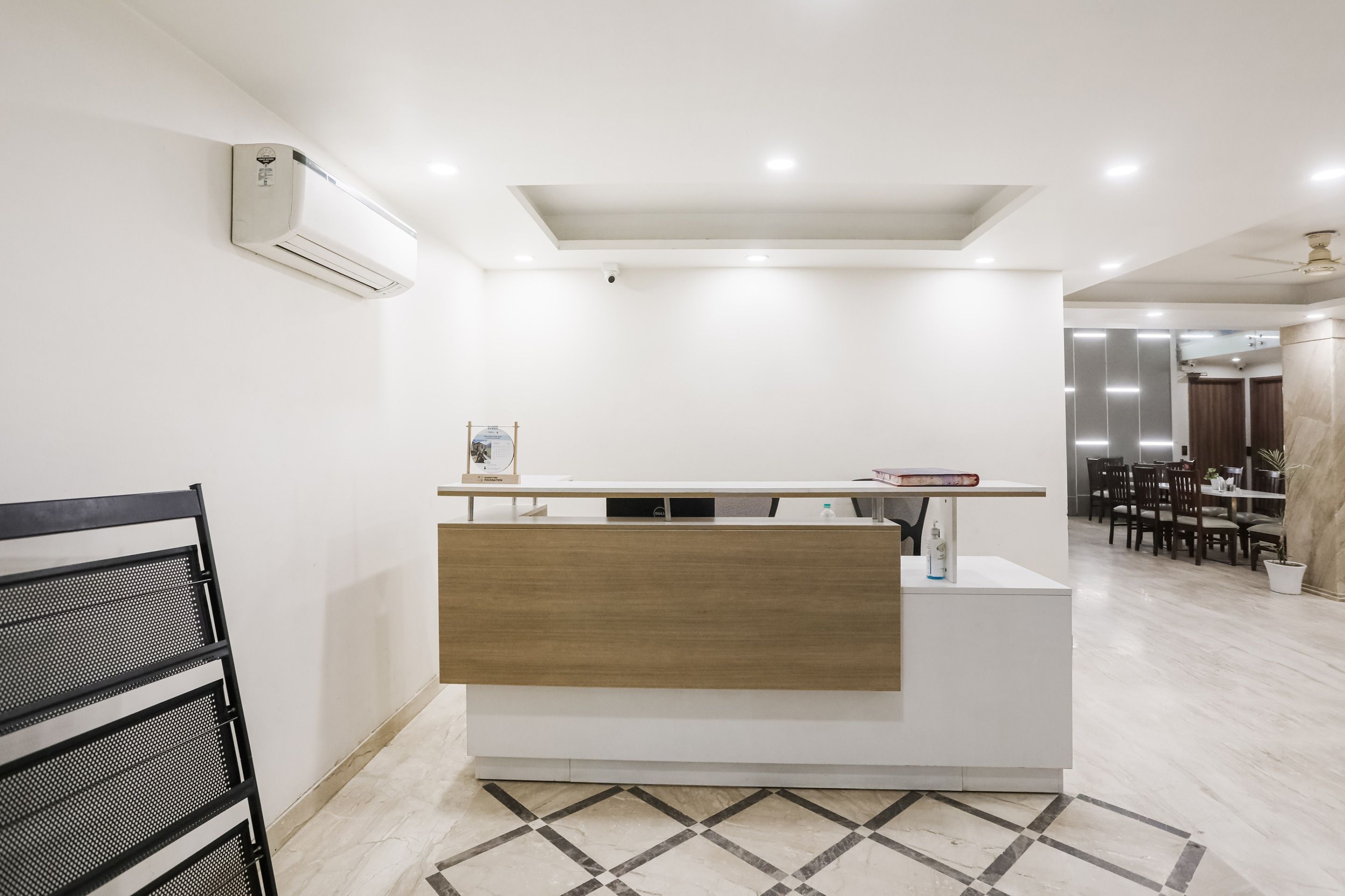 A reception desk with a wooden panel, a white wall, and a ceiling fan.
