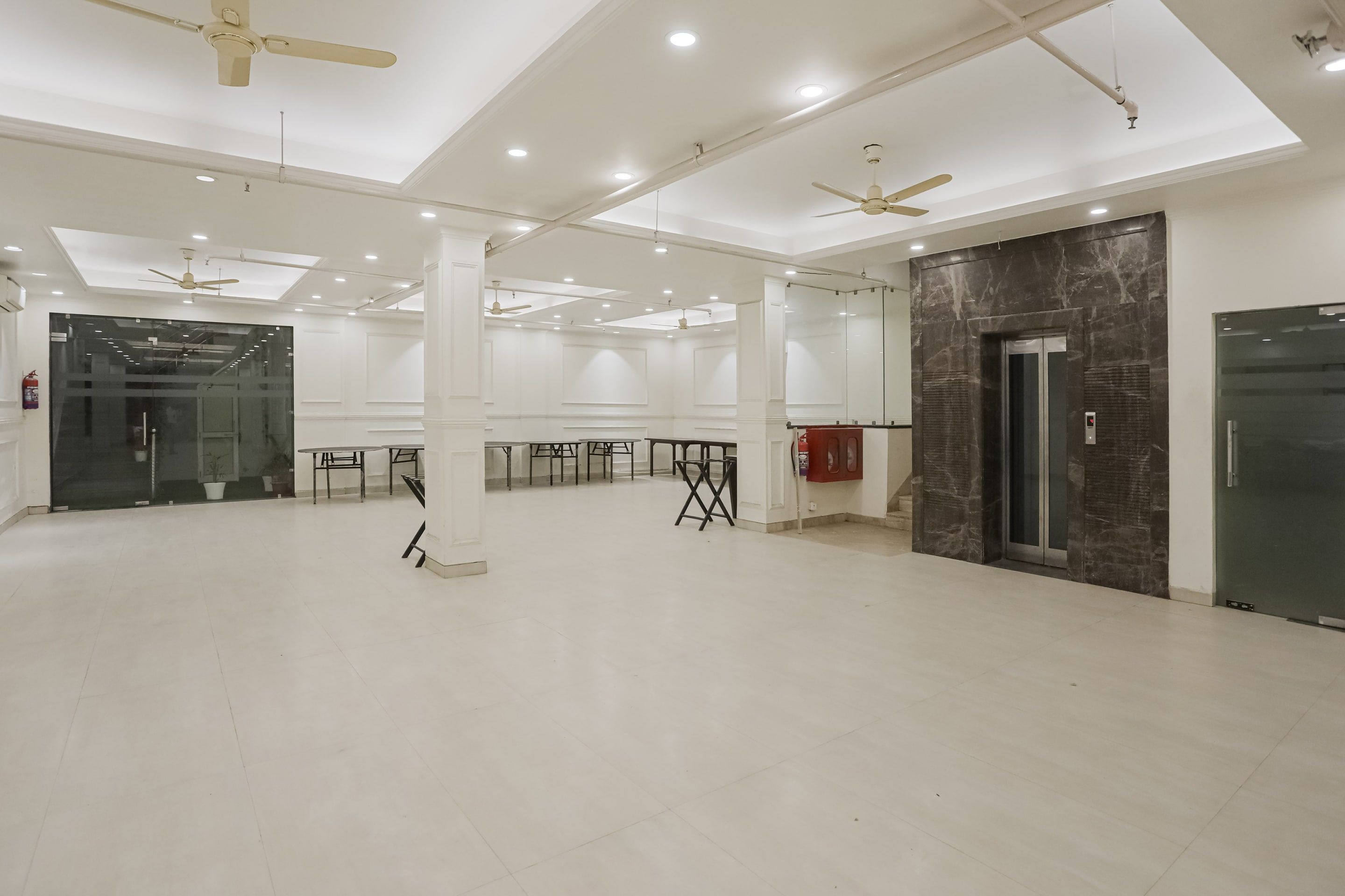 A spacious room with white walls, ceiling fans, and recessed lighting.
