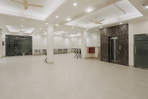 A spacious room with white walls, ceiling fans, and recessed lighting. - Townhouse The AMV Hotel (Gurugram)