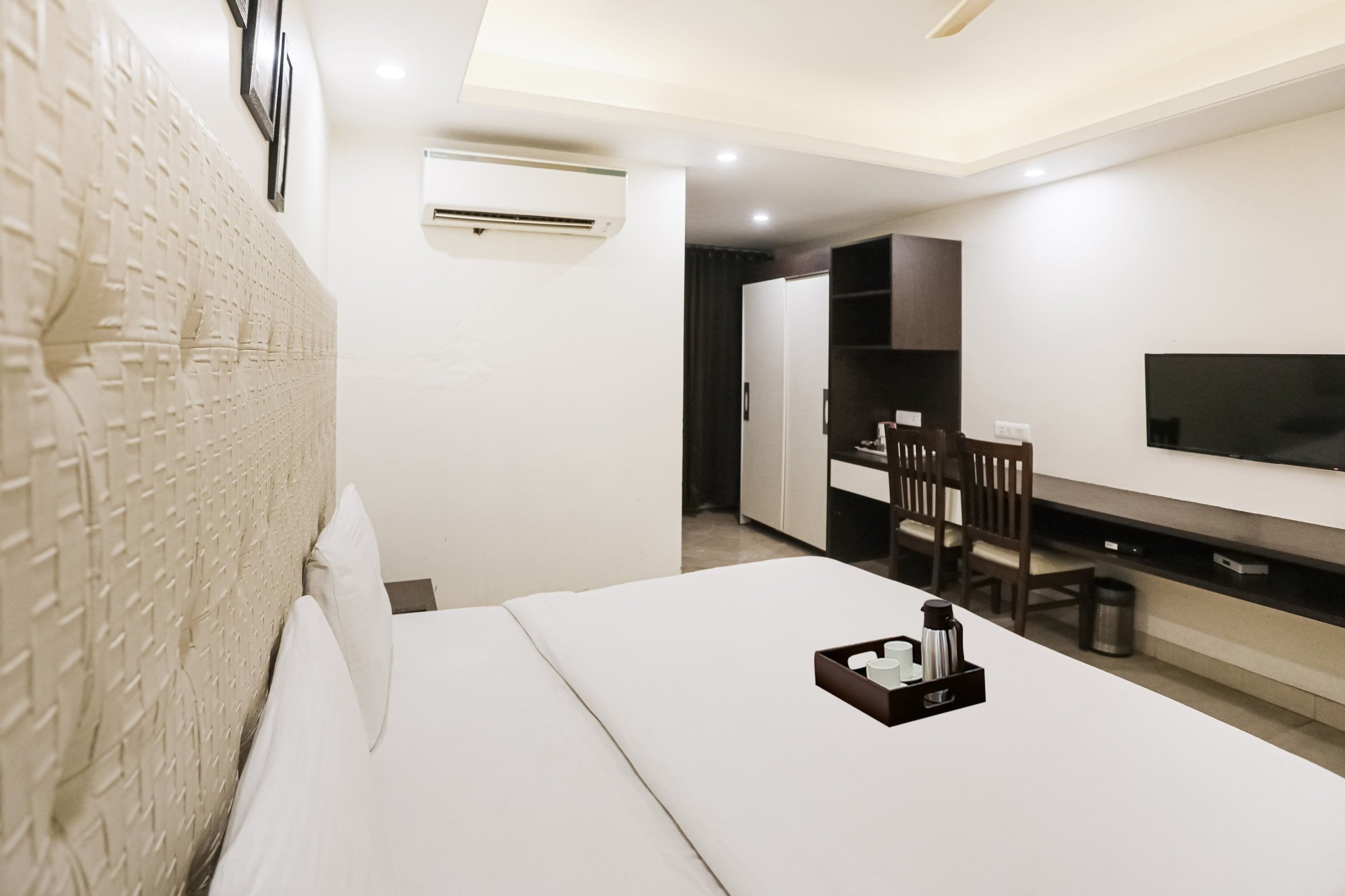 A hotel room with a bed, a TV, a desk, and a chair.