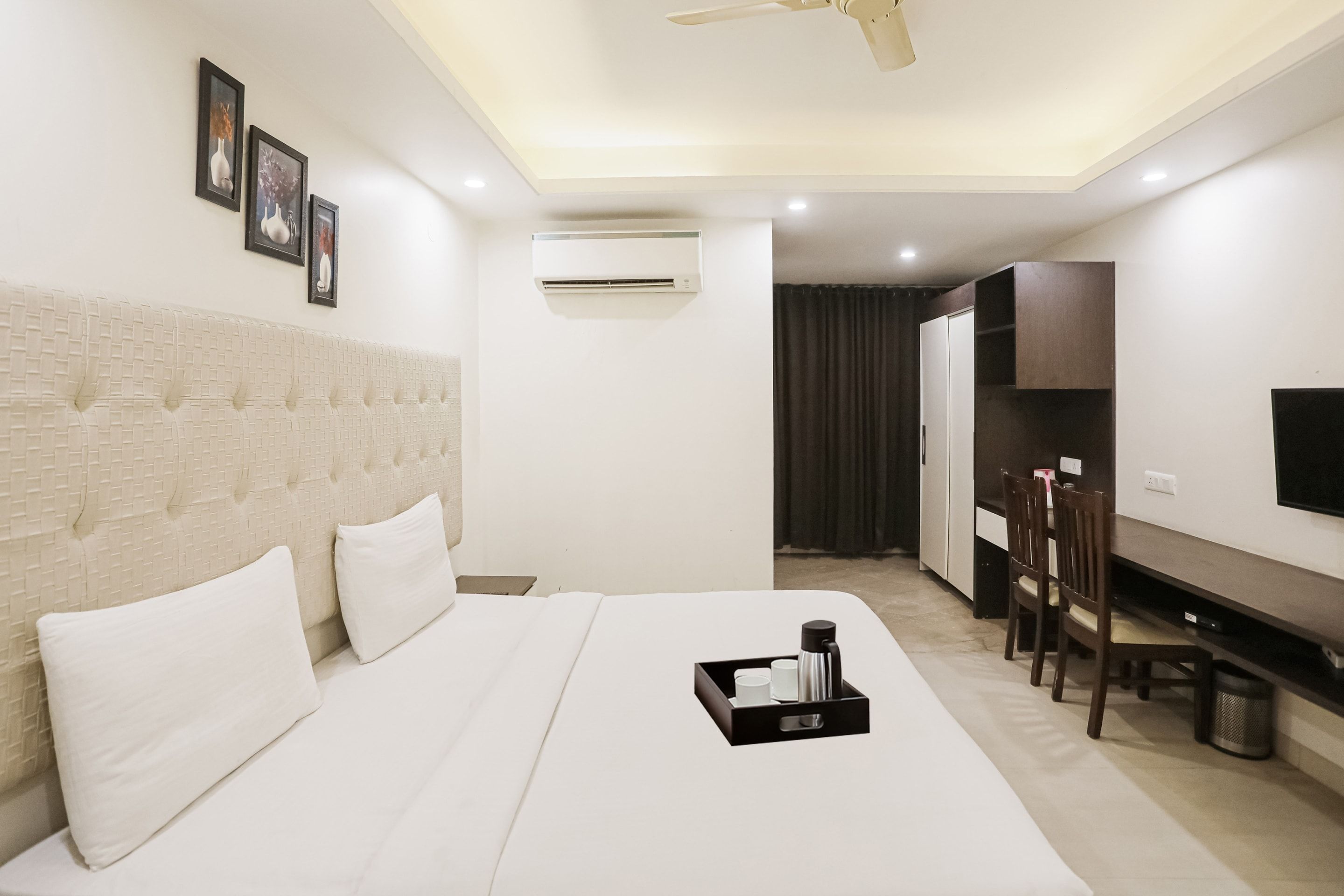 A hotel room with a bed, a desk, a TV, and an air conditioning unit.