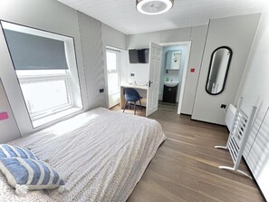 A modern bedroom with a large bed, a desk, and a bathroom in the background. - Standard Double Studio (Pembroke Dock)