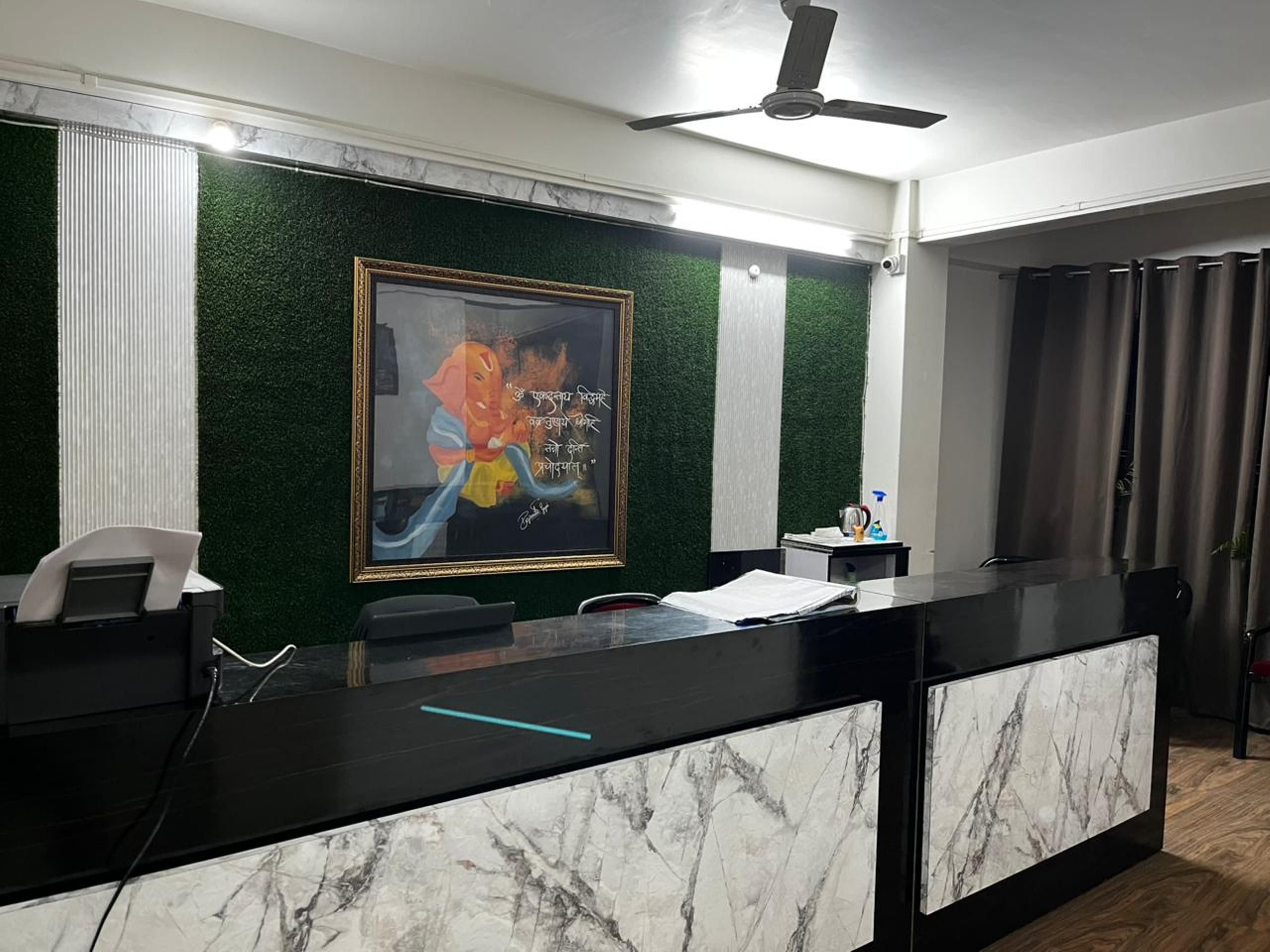 A reception desk with a marble front, a ceiling fan, and a framed artwork on the wall.
