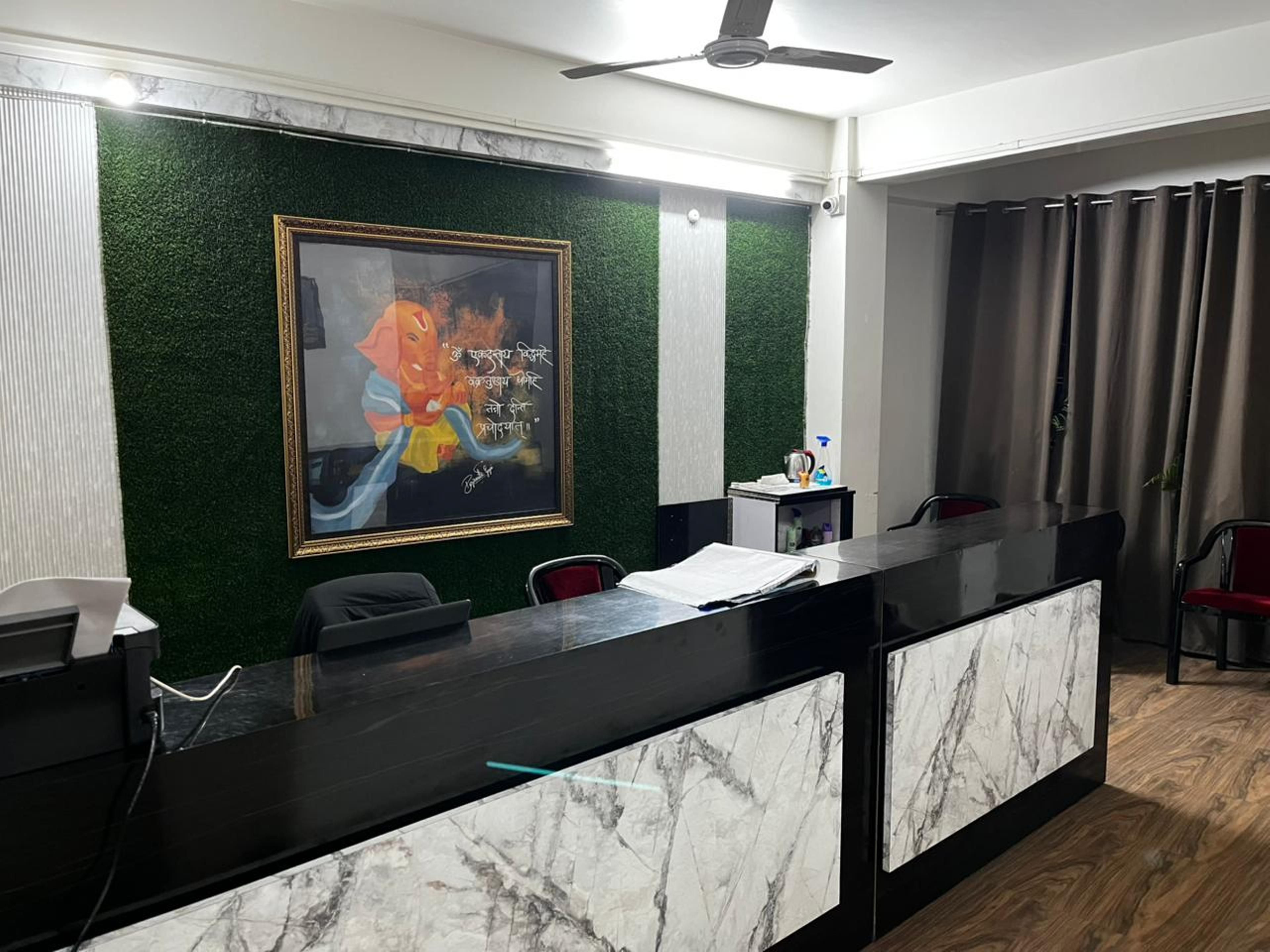 Un comptoir d’accueil agrémenté d’un mur végétal, d’un tableau encadré et d’un ventilateur de plafond.