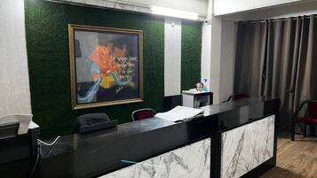 Un comptoir d’accueil agrémenté d’un mur végétal, d’un tableau encadré et d’un ventilateur de plafond.