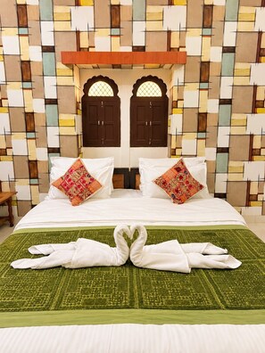 A hotel room with a bed, two pillows, a green bedspread, and a decorative swan made of towels. - Hotel Alexa Palace (Jaisalmer)