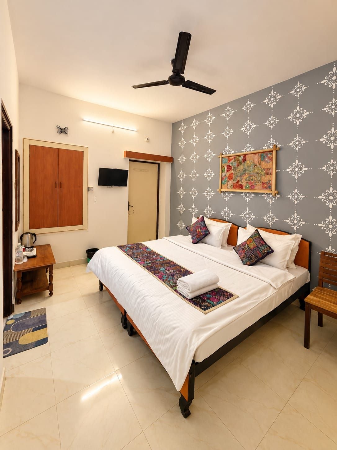 A neatly arranged bedroom with a bed, bedside tables, a ceiling fan, and a wall-mounted TV.
