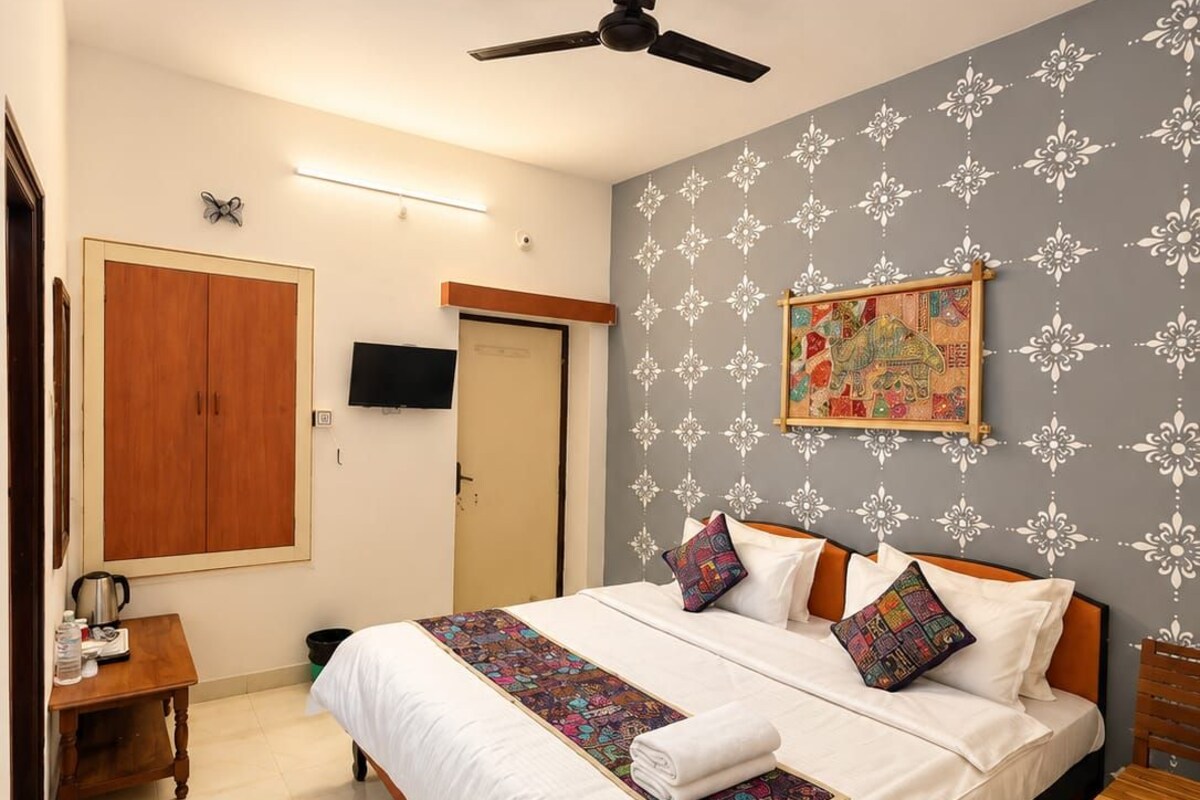 A neatly arranged bedroom with a bed, bedside tables, a ceiling fan, and a wall-mounted TV.