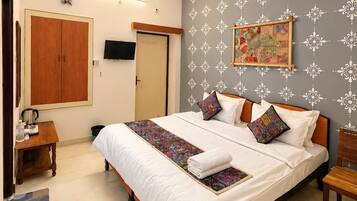 A neatly arranged bedroom with a bed, bedside tables, a ceiling fan, and a wall-mounted TV.